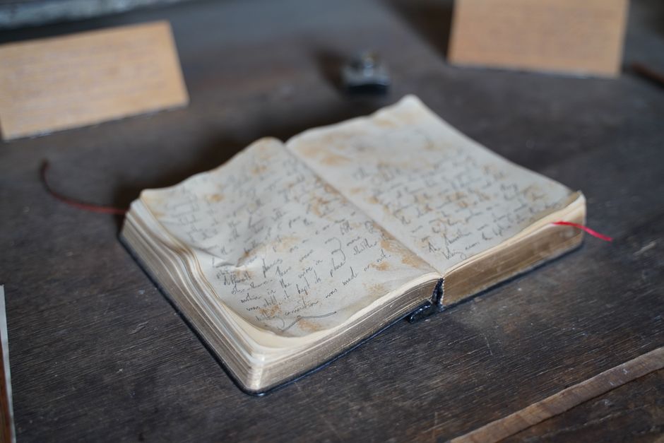 A close-up of an antique open book with handwritten pages on a rustic wooden table.